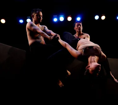 Tres bailarines del elenco de la CND realizando una acción de movimiento conjunta. 